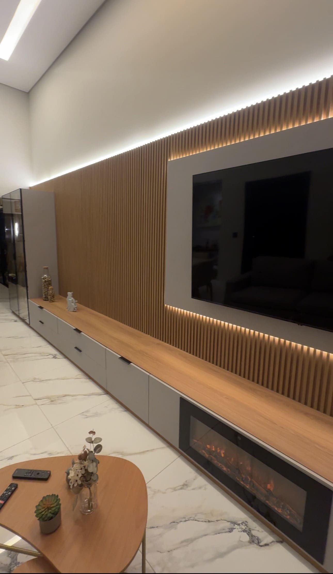 Painel de TV ripado com lareira, iluminacao indireta em LED, bancada em madeira e moveis planejados para sala em Piracicaba SP - Decora Sob Medida
